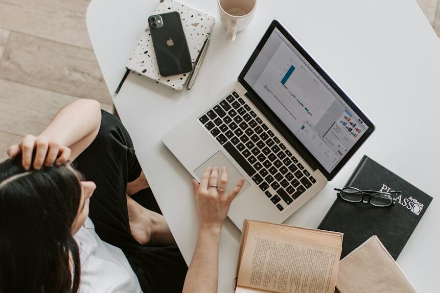 pexels-photo-4050320-4050320 From above of young woman with long dark hair in casual clothes working at table and browsing netbook while sitting in modern workplace and touching hair