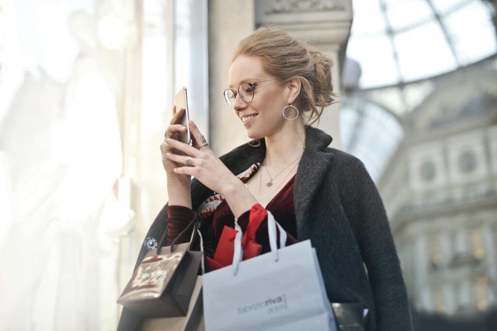 pexels-photo-994197-994197-1 Stylish woman with shopping bags using smartphone in Milano, Italy. Perfect urban tech and fashion capture.